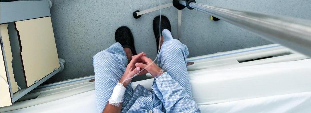 A Patient Sitting On An Exam Table With An IV In His Arm.